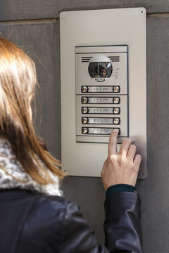 Woman pushing the button and talking on the intercom