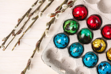 colored quail eggs for Easter in a box with willow branches