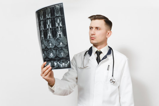 Focused handsome young doctor man holds x-ray radiographic image ct scan mri isolated on white background. Male doctor in medical uniform, stethoscope. Healthcare personnel, health, medicine concept.