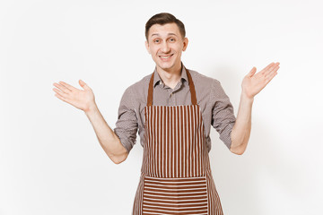 Young smiling happy man chef or waiter in striped brown apron, shirt spreading hands isolated on white background. Male housekeeper or houseworker looking camera. Domestic worker for advertisement.