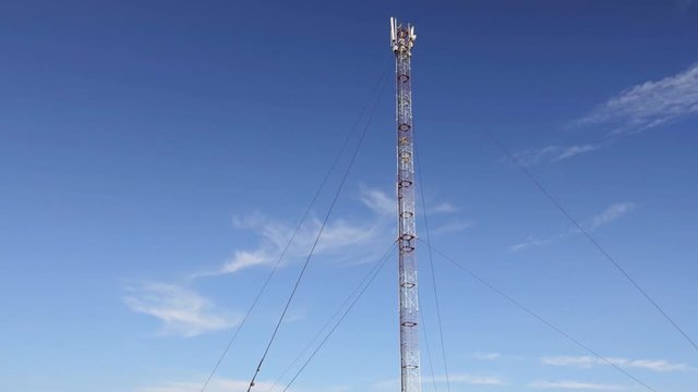 GSM or CDMA Antenna on a blue sky background, timelapse.