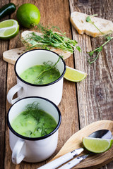 Cream soup with green pea, fresh herbs and sprouts with micro greens on top in rural mugs