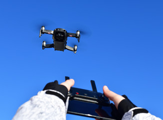 Quadrocopter flies in sky and hands with a control panel.