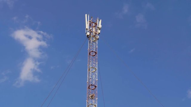 GSM or CDMA Antenna on a blue sky background, timelapse.