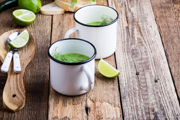 Cream soup with green pea, fresh herbs and sprouts with micro greens on top in rural mugs