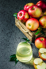 Apple cider and fresh apples in wooden box on concrete background. Selective focus, space for text.