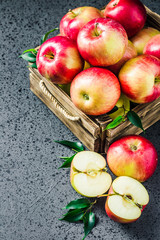Fresh apples in wooden box on concrete background. Selective focus, space for text.
