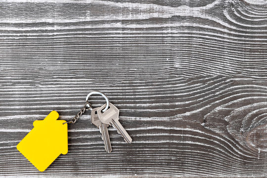 keys with a keychain in the form of a house on a wooden background.