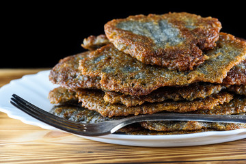 a stack of potato pancakes on a white plate on a wooden background. Home kitchen.