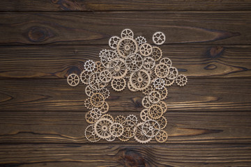 silhouette assembled house of gears on a background of natural wood texture. Mixed media, natural eco tree. symbol of house industry. repair and construction. business industry