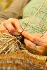 knitting scene of woman hands crocheting a wool vest and brown ball of wool