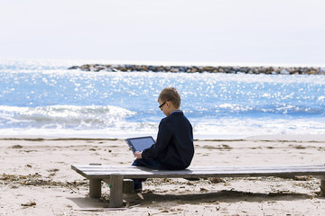 boy playing in the tablet on the seashore in the spring