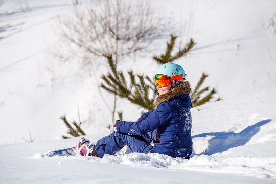 Photo of athlete in helmet with snowboard sitting at fir -tree