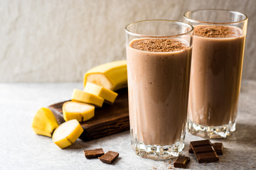 Chocolate banana smoothie in glass on gray stone background