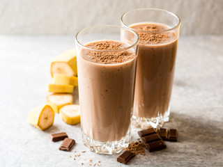 Chocolate banana smoothie in glass on gray stone background