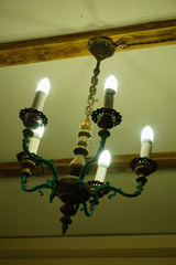 Old chandelier with five lamps hangs on the ceiling with a pre-revolutionary house. 