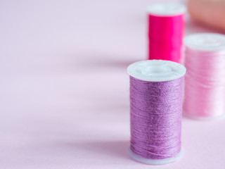 Colorful sewing buttons and thread on a pink background.