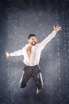 Attractive bearded young man jumping for joy under the rain