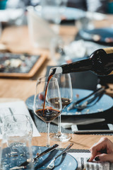 sommelier pouring red wine into glass at wine tasting