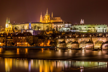 Illuminated city at night. Prague Castle and Charles Bridge 