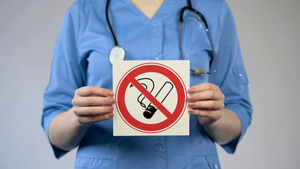Physician showing no smoking sign, specialist warning about harm of tobacco use