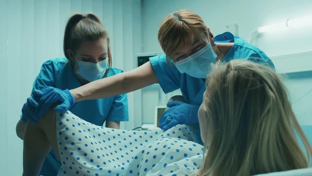 In the Hospital Woman in Labor Pushes to Give Birth, Obstetricians Assisting, Help Spreading Her Legs. Modern Maternity Ward with Professional Midwives.  Shot on RED EPIC-W 8K Helium Cinema Camera.