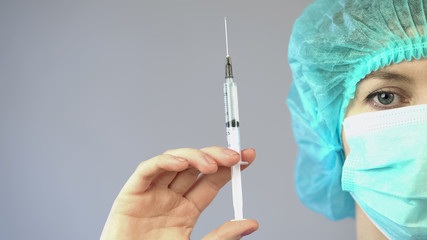 Female anesthetist holding syringe with medicine and preparing for surgery