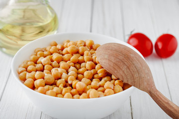 Cooked chickpeas with a plate, tomatoes and olive oil on a wooden table