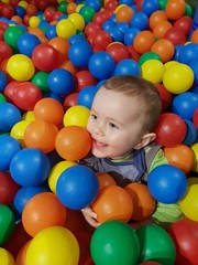 Fototapeta na wymiar Little boy with colourful balls in a soft play area