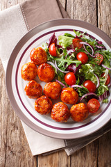 Delicious food: fried chicken meatballs salad of tomato, lettuce and onion close-up on a plate. Vertical top view