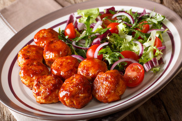 fried meatballs with salad of tomato, lettuce mix and onion close-up on a plate on the table. horizontal