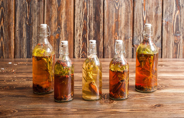 Spices bottled in oil on wooden background