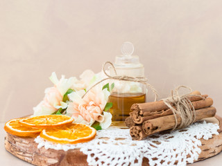 Made at home from orange oil with cinnamon perfume in a glass jar. Slices of dried orange, dried cinnamon and flowers. Crocheted white napkin. Perfumer.Natural and healthy cosmetic. Wooden background.