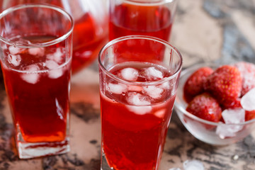 strawberry lemonade in a clear glass . cherry red juice in a glass and a decanter.
