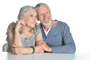 Portrait of hugging senior couple sitting at table