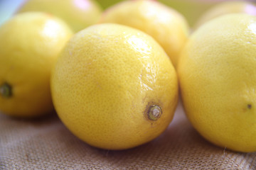 Some lemons on a burlap fabric on a wooden table in a rustic kitchen. Empty copy space for Editor's text.