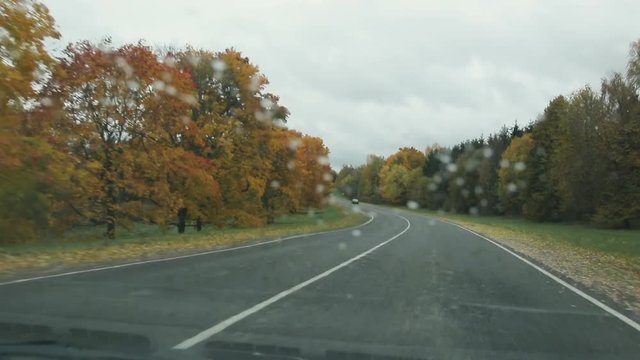 car rides on a country road in autumn in rainy weather, view from the front window