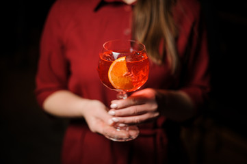 Woman dressed in a red shirt with a Aperol syringe summer cocktail