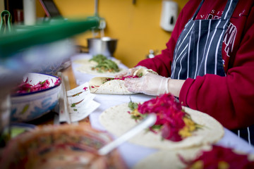Fresh and delicious chicken shish kebab being prepared hygienically in a burritos or fajitas wrap and covered with salad including red lettuce, grated carrots, rocket leaves
