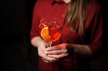 Woman dressed in a red shirt with a tasty Aperol syringe summer cocktail