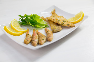 Fried fish on dish with lemon and salad. Typical sicilian food
