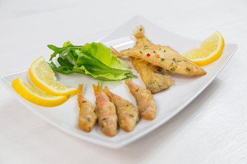Fried fish on dish with lemon and salad. Typical sicilian food