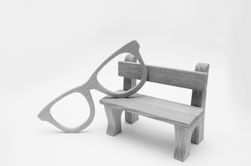 concept of old age, wooden model bench  with wooden glasses on a white background, wisdom,...