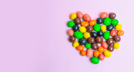 heart of sweets, colorful candies on a pink background, sweet food. the concept of love. banner. copy space