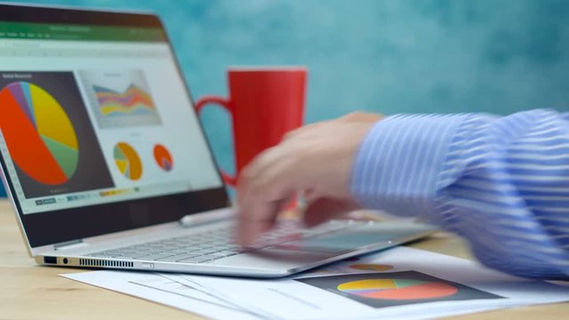 Accountant businessman working at desk with graphs and modern touch screen technology laptop.