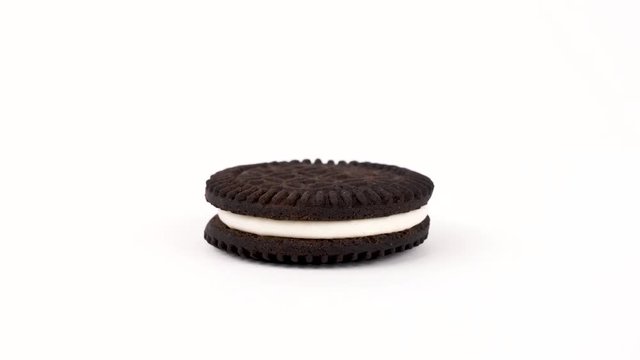 Two chocolate wafers separated by a cream filling cookie isolated on white background. Rotating on a turn table. Loopable. Popular vegan dessert.