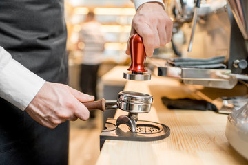Pressing a coffee with temper into the handle of the professional coffee machine