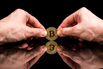 bitcoin in hand on a black background. Mirror reflection of a coin