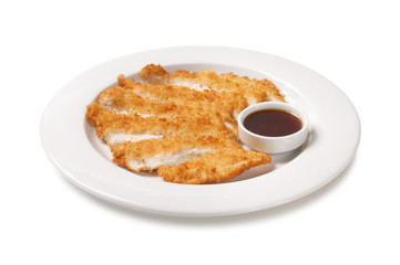 Breaded and fried chicken pieces with sauce in a plate on a white background