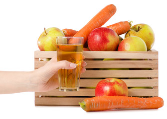 Wooden box of apples carrots glass of juice in hand